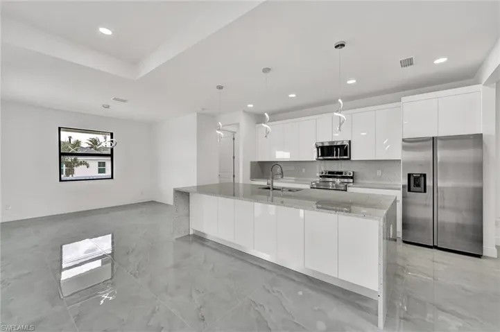 Kitchen featuring stainless steel appliances, modern cabinets, white cabinetry, recessed lighting, and backsplash