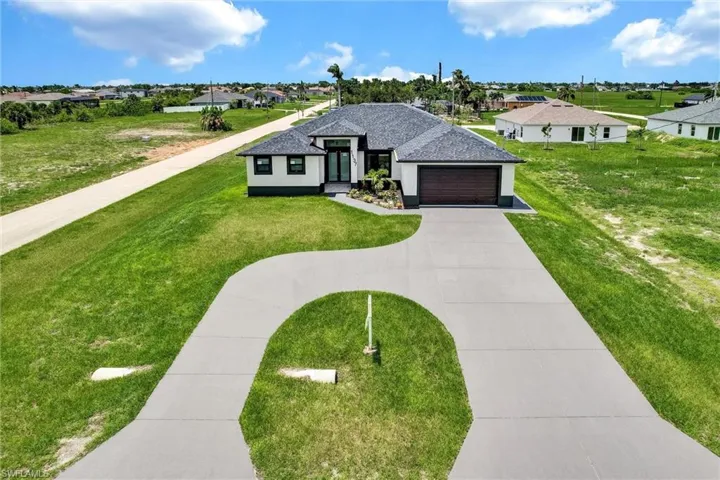 View of front facade featuring an attached garage, a residential view, concrete driveway, a shingled roof, and a front lawn