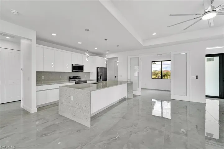 Kitchen with appliances with stainless steel finishes, modern cabinets, white cabinets, a spacious island, and recessed lighting