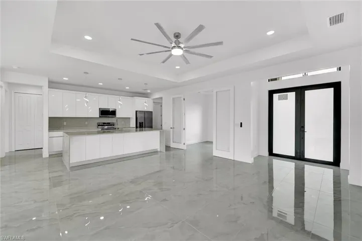 Kitchen featuring appliances with stainless steel finishes, a raised ceiling, recessed lighting, a ceiling fan, and french doors