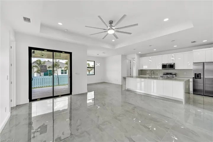 Kitchen with stainless steel appliances, a tray ceiling, modern cabinets, recessed lighting, and white cabinets