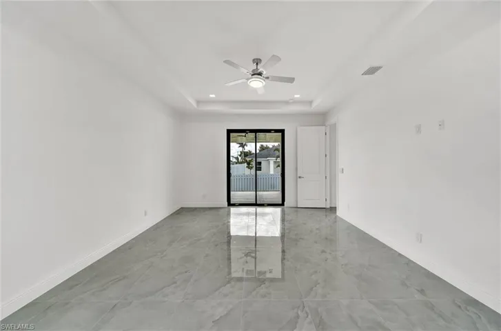 Empty room with a ceiling fan, recessed lighting, a tray ceiling, and light marble finish flooring