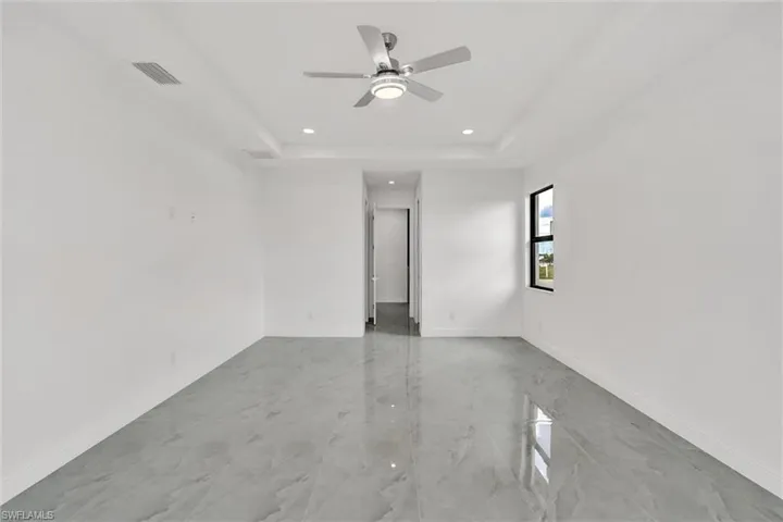 Unfurnished room with a ceiling fan, a tray ceiling, recessed lighting, and light marble finish flooring