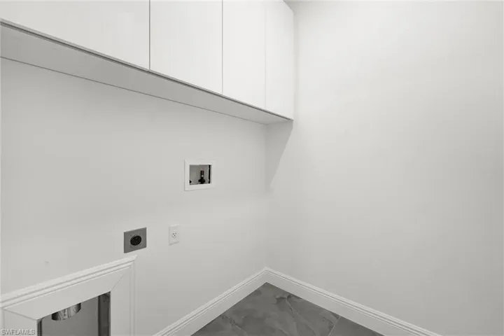 Laundry area with cabinet space, electric dryer hookup, hookup for a washing machine, and dark marble finish flooring