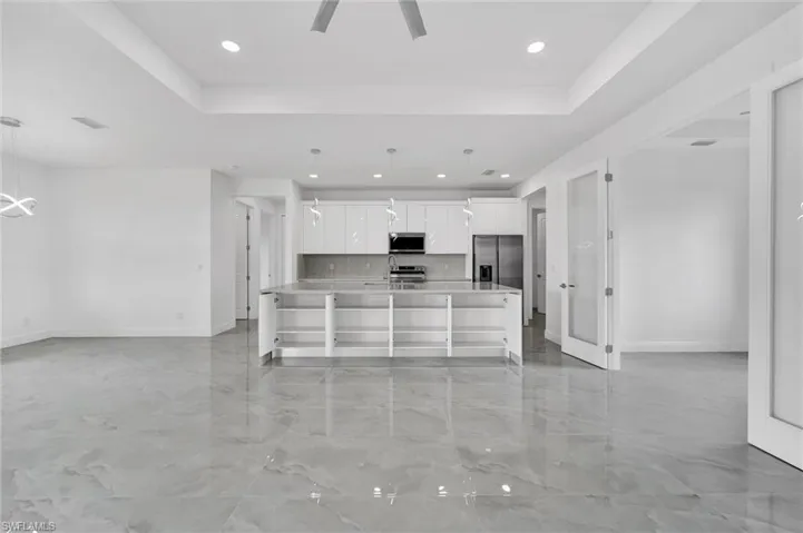Kitchen with stainless steel appliances, white cabinetry, recessed lighting, light countertops, and open floor plan