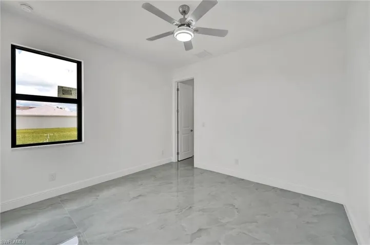 Unfurnished room featuring a smoke detector, light marble finish floors, and a ceiling fan