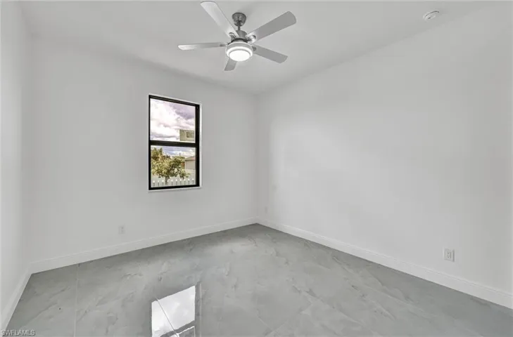Spare room featuring light marble finish flooring and ceiling fan
