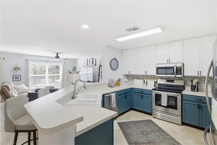 Kitchen with dual tone cabinetry, stainless steel appliances, open floor plan, a peninsula, and backsplash