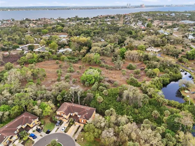 Aerial view of residential area with a nearby body of water and a tree filled landscape