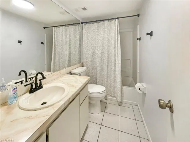 Full bathroom featuring vanity, shower / bath combo with shower curtain, and light tile patterned flooring