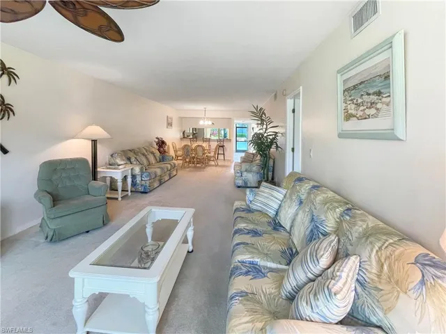 Living room with light carpet and suspended lighting