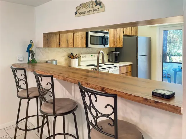 Kitchen with wooden counters, a peninsula, stainless steel appliances, backsplash, and wood finish cabinetry