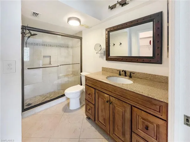 Full bathroom featuring vanity, a stall shower, and light tile patterned floors