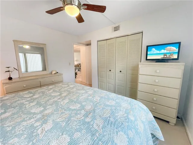 Bedroom with ceiling fan, a closet, and light colored carpet