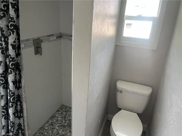 Full bathroom featuring a stall shower and a textured wall