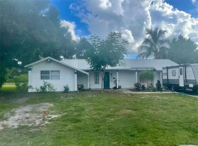 Ranch-style home with a metal roof and a front lawn