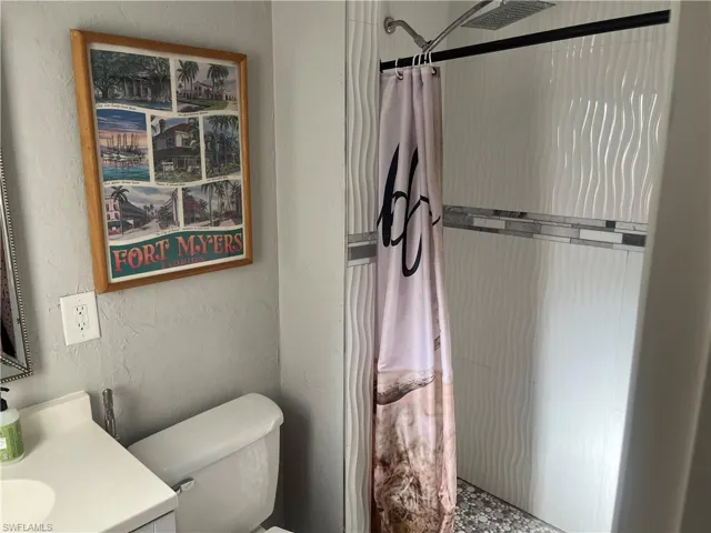 Bathroom with a stall shower, a textured wall, and vanity