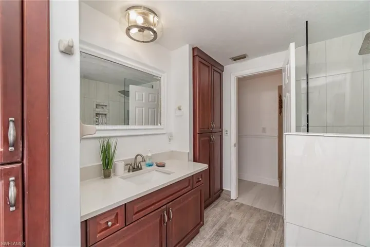 Bathroom with vanity, walk in shower, and wood-type flooring