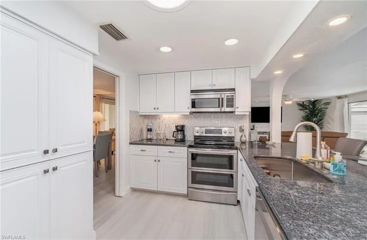 Kitchen featuring white cabinets, tasteful backsplash, stainless steel appliances, and sink