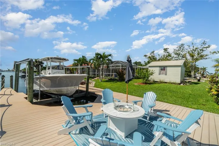Dock area featuring a lawn, a water view, glass enclosure, and a fire pit