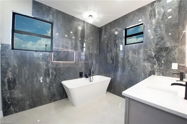 Bathroom featuring vanity, a bath, and tile walls