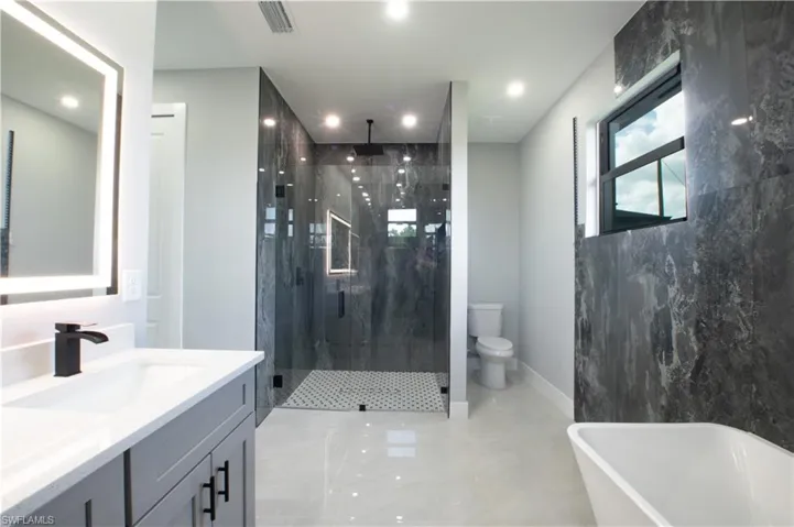 Full bathroom featuring toilet, shower with separate bathtub, and vanity