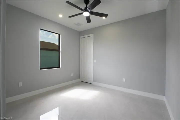 Tiled spare room featuring ceiling fan