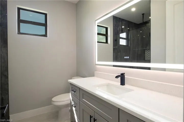 Bathroom featuring vanity, toilet, a tile shower, and tile patterned floors