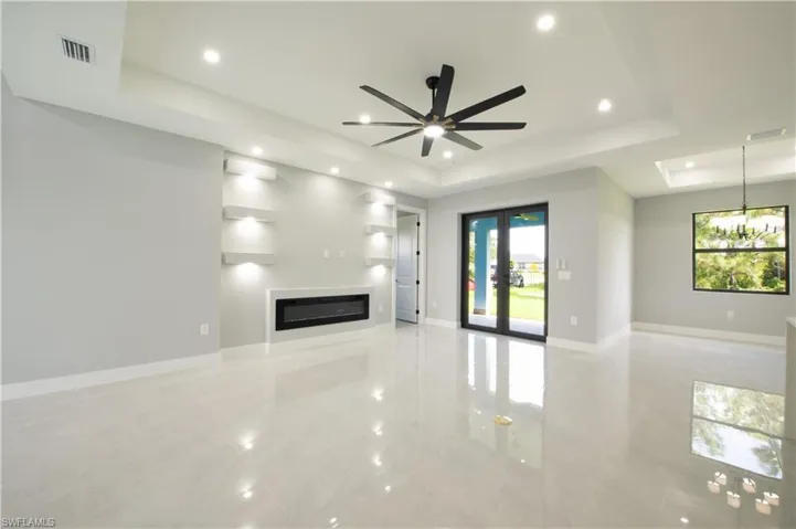 Unfurnished living room with a tray ceiling, a healthy amount of sunlight, and ceiling fan