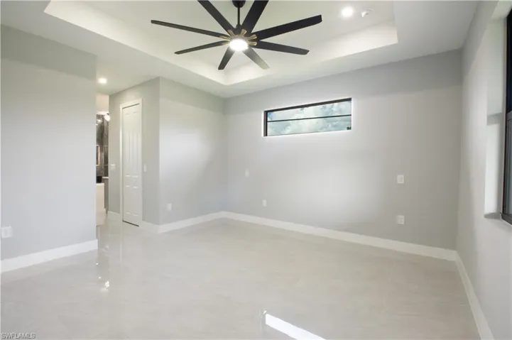 Empty room featuring a tray ceiling and ceiling fan