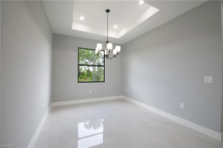 Empty room with a tray ceiling and a notable chandelier