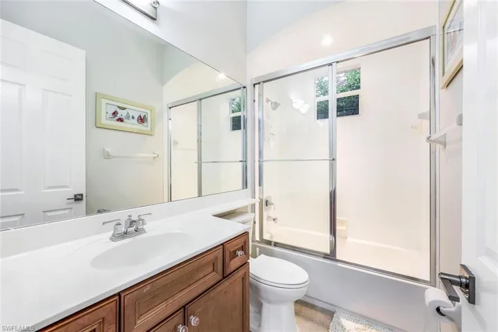 Full bathroom featuring vanity, combined bath / shower with glass door, and toilet
