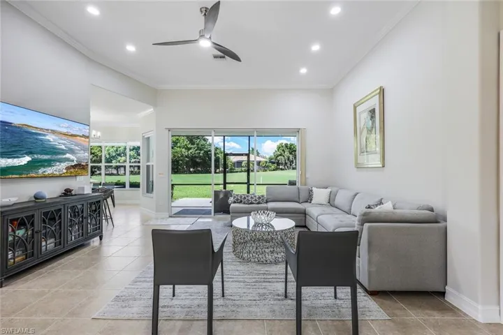 Tiled living room with ceiling fan and crown molding