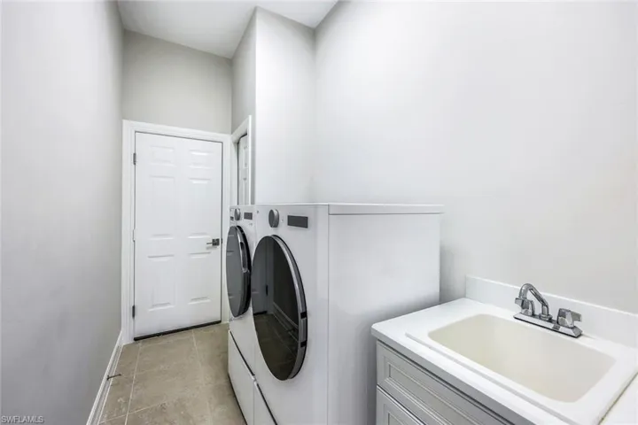Laundry room with sink, washer and dryer, and light tile patterned floors