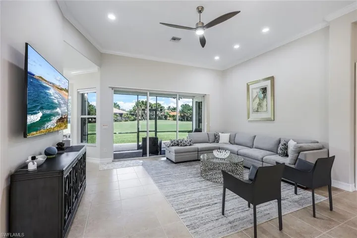 Living room with light tile patterned floors, ceiling fan, and crown molding