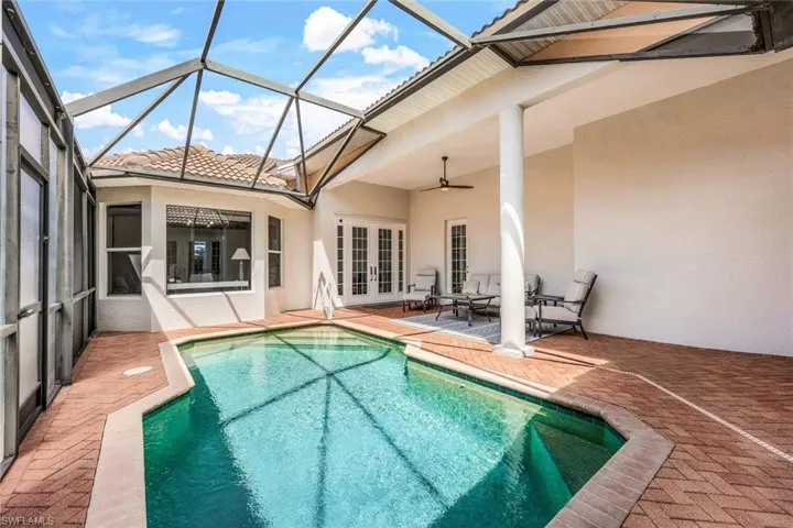 View of pool with a patio area, ceiling fan, french doors, and glass enclosure