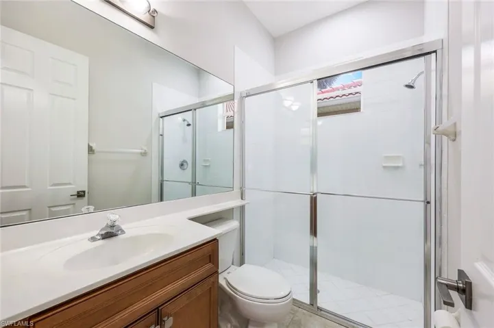 Bathroom with a shower with door, vanity, and toilet