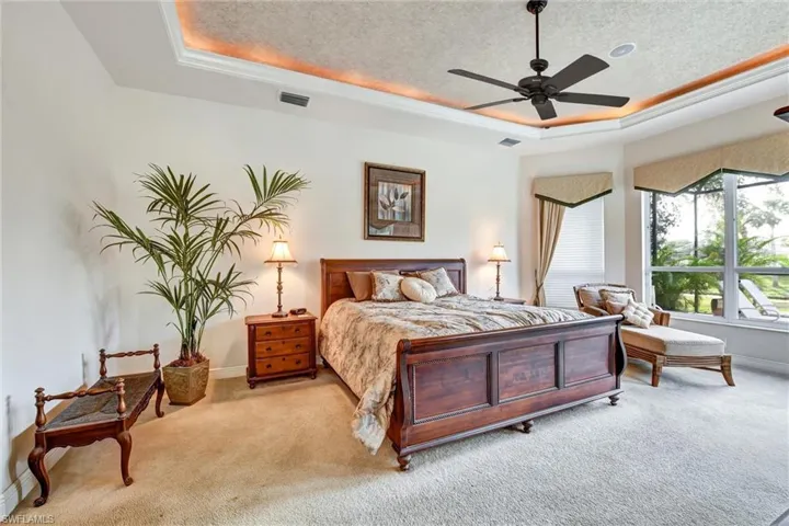 bedroom with a textured ceiling, a tray ceiling, ceiling fan, and crown molding