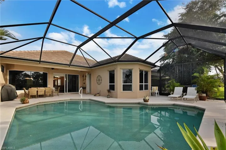 View of pool with  enclosure, a patio area, and ceiling fan