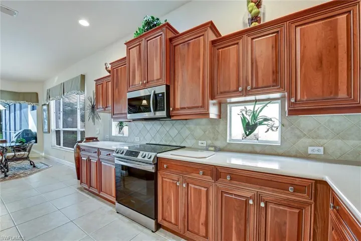 Kitchen featuring backsplash, stainless steel appliances, and light tile patterned flooring