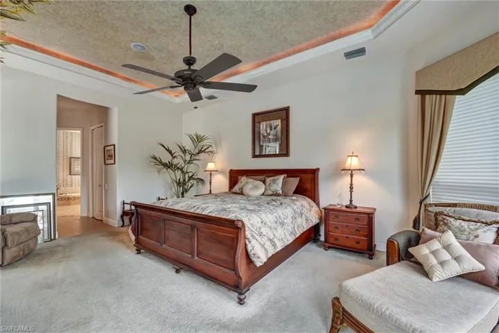 Main bedroom featuring a raised ceiling, connected bathroom, ceiling fan, and a textured ceiling