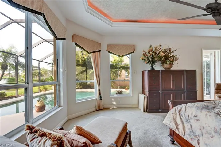 bedroom featuring ceiling fan, multiple water view, and a tray ceiling