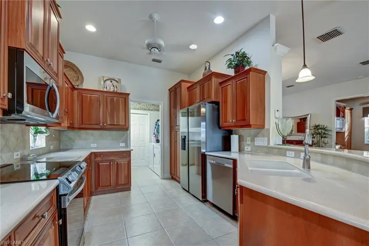 Kitchen featuring appliances with stainless steel finishes, tasteful backsplash, sink, light tile patterned floors, and pendant lighting