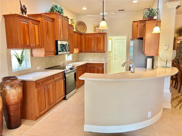 Kitchen featuring pendant lighting, light tile patterned floors, kitchen peninsula, and appliances with stainless steel finishes