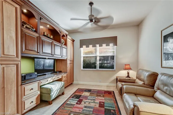 Tiled office featuring ceiling fan and built in desk