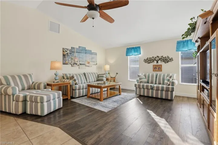 Living area with lofted ceiling, a ceiling fan, and light wood-style floors
