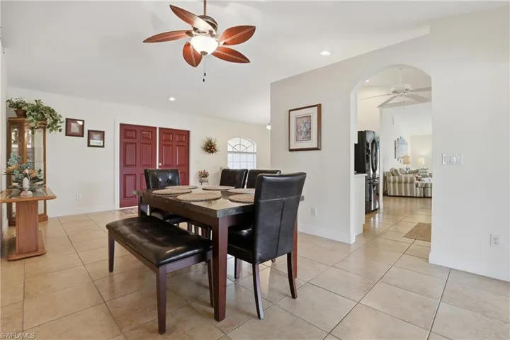 Dining space featuring ceiling fan, light tile patterned floors, recessed lighting, and arched walkways