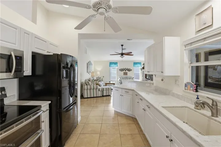 Kitchen featuring appliances with stainless steel finishes, light stone countertops, open floor plan, and white cabinets