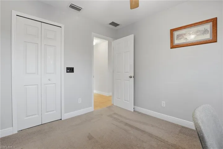 Carpeted bedroom featuring ceiling fan and a closet