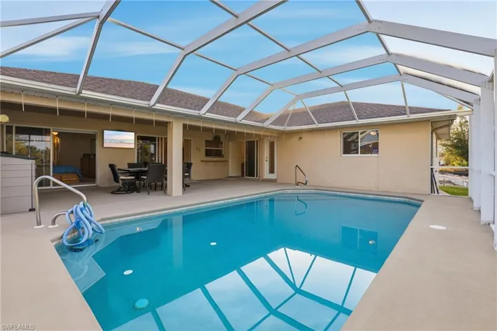 Swimming pool featuring a sunroom, glass enclosure, outdoor dining space, and a patio